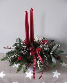 two red candles sitting on top of a christmas centerpiece