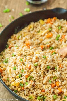 a pan filled with rice and vegetables on top of a wooden table