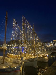 a sailboat is decorated with christmas lights in the harbor