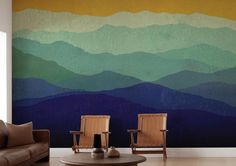 two chairs sitting in front of a wall with mountains painted on it