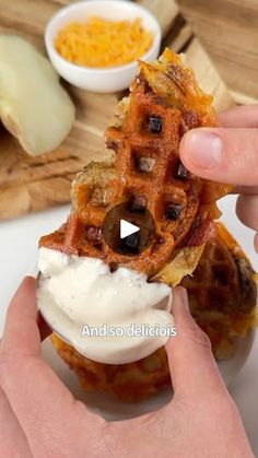 a person is holding up a waffle sandwich with cream cheese and olives on it