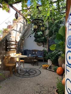 an outdoor patio with potted plants and tables in the center, surrounded by greenery