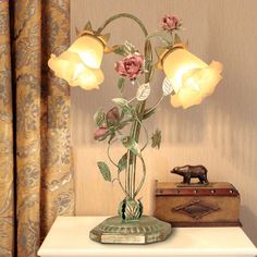 a vase with flowers on top of a table next to a box and lamp shade