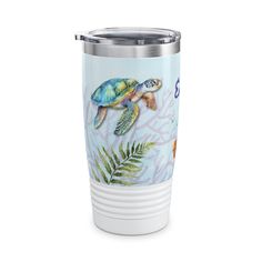 a blue and white tumbler cup with sea turtles on the side, surrounded by palm leaves