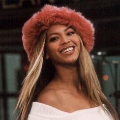 a woman with long hair wearing a pink hat and white shirt smiling at the camera