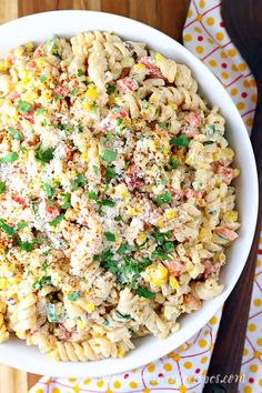 a white bowl filled with pasta salad on top of a wooden table