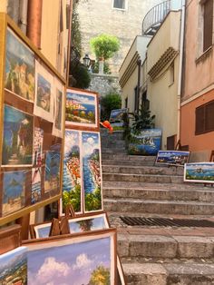 several paintings are on display in front of some buildings and stairs with steps leading up to them