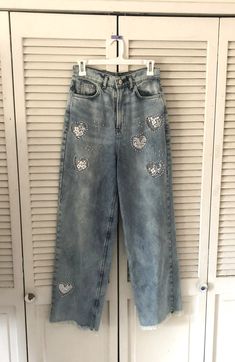 "These are stonewashed jeans made in Argentina. I have cut out hearts and embellished behind the hearts with white lace and sewn on pearl beads. They have frayed edge hems and 5 pockets. Good quality, never worn jeans. Better to wash on sensitive and hang dry. Please check sizing, label says size 28 which is like an 8 I think.  Very High rise. Waist is 28 \" Inside leg 29 \" Legs are quite wide about 10 \" I will ship in a day." Embellished Denim Blue Straight Leg Jeans, Embellished Straight Leg Denim Blue Jeans, Denim Blue Straight Leg Jeans With Rhinestones, Denim Blue Rhinestone Straight Leg Jeans, Embellished Denim Blue Straight Leg Bottoms, Embellished Straight Leg Denim Pants, Spring Denim Blue Jeans With Rhinestones, Spring Rhinestone Denim Blue Jeans, Straight Leg Denim Bottoms With Sequins