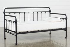 a black metal daybed with white sheets on it's sides and two pillows