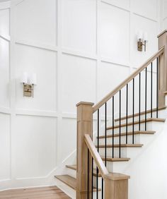 a wooden stair case with metal handrails in a white painted wall and wood flooring