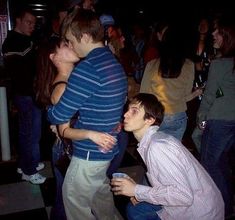 two young men kissing each other in front of a group of people at a party