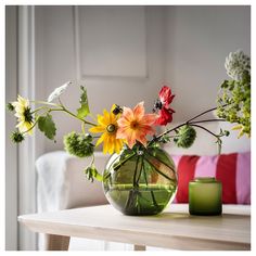 a vase filled with flowers sitting on top of a table next to a green candle