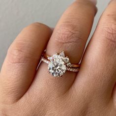 a woman's hand with a diamond ring on top of her finger and the other hand holding an engagement ring