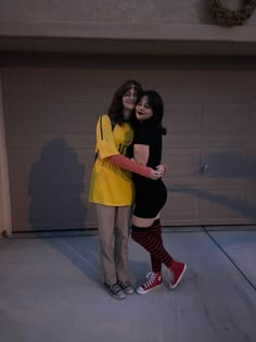 two young women standing next to each other in front of a garage door with their arms around one another