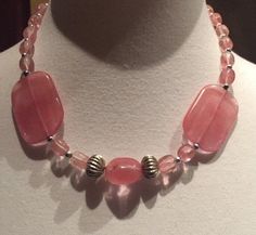 I would consider this 16"  pink necklace a choker since it hangs by the neck. The two large flat beads make a nice contrast to the other smaller beads. The perfect necklace to brighten your day. No maker is on this piece. In very good vintage condition. These beads look like stone but I'm pretty sure they are plastic of some sort. The shipping weight will be 4 ounces. Pink Necklaces With Polished Beads For Gifts, Pink Polished Beaded Necklaces For Gifts, Pink Necklace With Polished Beads For Gift, Pink Polished Bead Necklace For Gift, Pink Handmade Choker With Round Beads, Handmade Pink Choker With Round Beads, Adjustable Single Strand Pink Beaded Necklace, Adjustable Pink Necklace With Gemstone Beads, Adjustable Pink Gemstone Beads Necklace