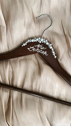 a wedding dress hanger with the words happy bride written on it and pearls attached to it