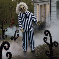 a creepy man in striped suit standing next to bushes