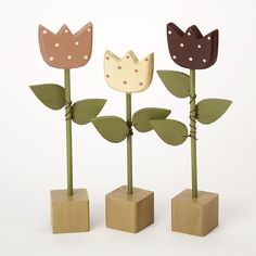 three wooden flowers with leaves in them on top of each other and one has a crown on it's head