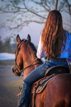 a woman riding on the back of a brown horse