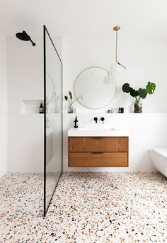 a bathroom with a sink, mirror and bathtub next to a shower head mounted on the wall