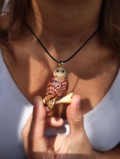 a woman holding an owl figurine in her right hand while wearing a necklace