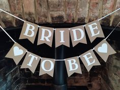 a bride to be banner hanging from a pole in front of a fire place with hearts on it