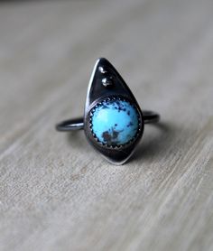 This small, round, blue turquoise is set in a fine silver serrated bezel and set on a rounded diamond backplate with silver bead details. This ring was dipped in a patina to give it an antiqued, matte look. It is a US size 7.25. Blue Sterling Silver Ring With Patina, Blue Sterling Silver Rings With Patina, Handmade Rustic Silver Turquoise Ring, Blue Patina Sterling Silver Jewelry, Blue Sterling Silver Jewelry With Patina, Blue Teardrop Patina Jewelry, Blue Teardrop Jewelry With Patina, Rustic Silver Turquoise Ring For Gift, Rustic Silver Turquoise Ring Gift