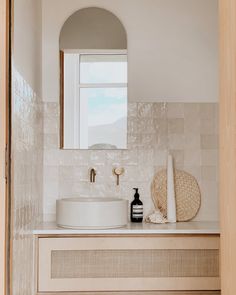 a white sink sitting under a bathroom mirror next to a wooden cabinet and counter top