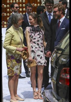 two women and one man are standing next to each other in front of a car