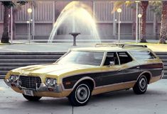 an old station wagon parked in front of a fountain