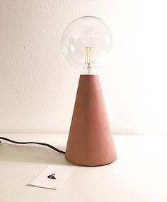 a pink lamp sitting on top of a white table next to a mouse and keyboard