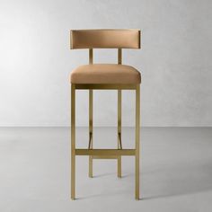 a gold colored bar stool with a tan upholstered backrest and seat cushion