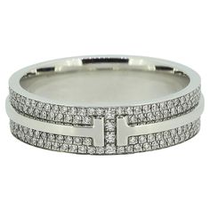 Here we have a a fabulously crafted diamond band ring from the world renowned jewellery designer Tiffany & Co. This ring forms part of their T True collection and is the wider model featuring the iconic T motif around the entire band with two rows of pavé set diamonds for company. Condition: Used (Excellent) - Professionally polished to appear brand new Weight: 8.0 grams Ring Size: S (60) Band Width: 5.8mm Total Diamond Weight: Approx. 0.56ct Diamond Details: Approx. Colour: F-G, Clarity: VS Band Width: 3.5mm Marked: ‘Tiffany & Co.’ ‘Au750’ 'ITALY' RRP: £9,950 Box: Tiffany & Co. Box Tiffany Diamond Band Ring, Tiffany Wide Band Ring, Wide Diamond Rings, Tiffany Diamond Ring, Tiffany Setting, Tiffany T, Tiffany Diamond, Contemporary Engagement Rings, Diamond Band Ring