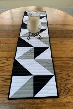 a black and white table runner with a candle on it, sitting on top of a wooden table