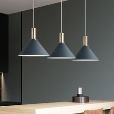 three pendant lights hanging from the ceiling above a dining room table with chairs and stools