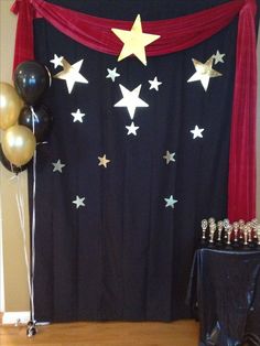 a black and gold themed party with balloons, cake table and curtain in the background