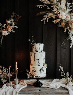 a white wedding cake sitting on top of a wooden table next to two tall candles