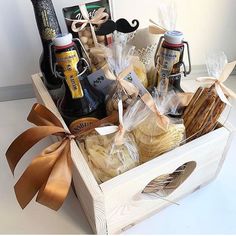 a wooden box filled with different types of food and wine bottles on top of a table