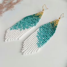 These long beaded earrings feature a green-and-white color scheme with a diagonal gradient. Handmade with meticulous attention to detail, they exude sophistication and elegance. Perfect for completing your ensemble with chic and style. Dimensions: - Length: 10 cm (3.9 inches) - Width: 3 cm (1.2 inches) Green Chandelier Earrings With Dangling Beads For Festivals, White Long Drop Earrings With Colorful Beads, White Teardrop Beaded Earrings With Faceted Beads, Green Dangle Chandelier Earrings For Festival, Bohemian Green Long Drop Earrings, White Chandelier Earrings With Dangling Beads For Festivals, White Dangle Earrings With Faceted Beads, White Bohemian Long Drop Earrings, Art Selling