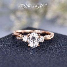 an engagement ring with three stones on it, sitting on top of a black surface