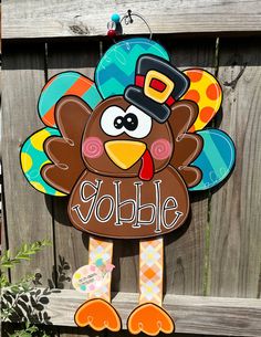 a turkey with a hat and name on it's head is standing in front of a fence