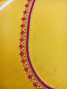 a yellow dress with red trim and beading on the neckline is seen in close up