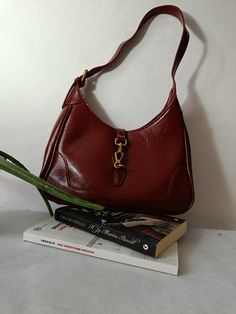 This vegan leather bag is an elegant and versatile accessory, perfect for any occasion. Crafted from burgundy leather, it stands out for its classic half-moon design, combining style and functionality. The closure is enriched with a gold metal detail, which adds a touch of sophistication. The bag's simple, clean lines make it suitable for both casual and formal wear. The shoulder strap is comfortable and durable, providing convenience for everyday use. Ideal for those who love vintage style, this bag goes perfectly with any outfit, adding a sophisticated touch. Trendy Burgundy Shoulder Bag For Everyday, Classic Burgundy Shoulder Bag For Fall, Burgundy Shoulder Bag For Fall, Trendy Everyday Burgundy Shoulder Bag, Retro Burgundy Shoulder Bag, Retro Burgundy Shoulder Bag For Everyday, Retro Burgundy Shoulder Bag For Daily Use, Retro Burgundy Bags For Daily Use, Burgundy Satchel Shoulder Bag For Fall