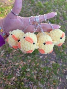 three small stuffed animals are being held by a person's hand in the grass