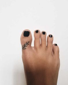 a woman's foot with black nail polish and leaves on the tip of her toe