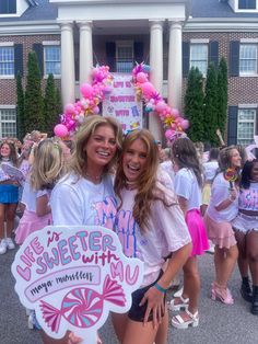 two women standing next to each other in front of a building with balloons on it