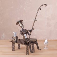 a metal sculpture of a fishing man sitting on a bench next to a fish hook