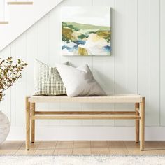 a bench with pillows on it in front of a stair case next to a plant