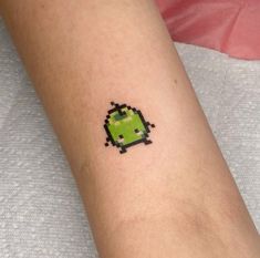 a small pixel tattoo on the arm of a person's arm, with an image of a green apple