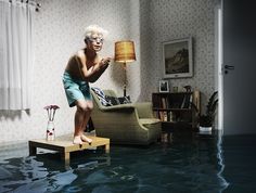 a man standing on top of a wooden table in the middle of a flooded living room